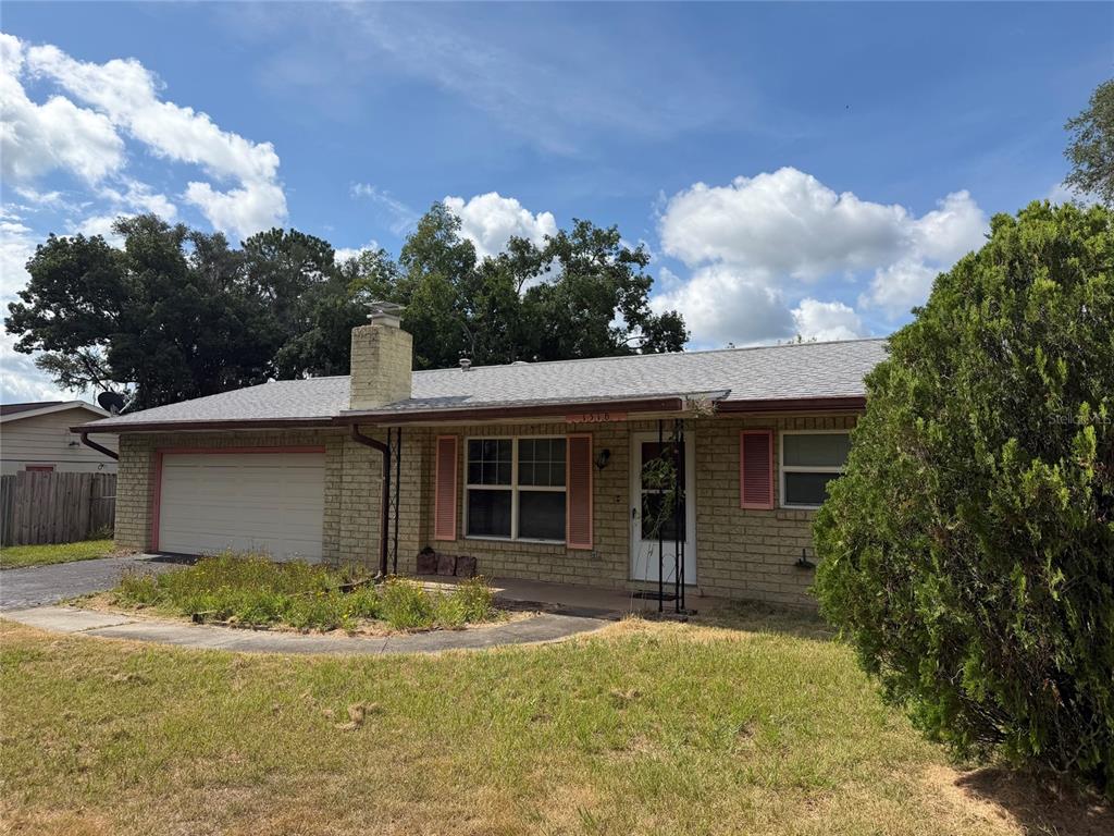 A single-story brick house with a garage, chimney, and front lawn under a blue sky — 1316 SE 17TH STREET, OCALA, FL