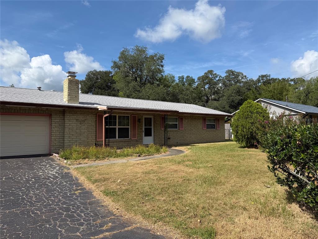 A single-story brick house with a garage and a driveway under a blue sky — 1316 SE 17TH STREET, OCALA, FL