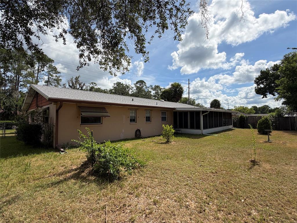The exterior of a single-story house with a screened-in porch and a grassy backyard — 1316 SE 17TH STREET, OCALA, FL