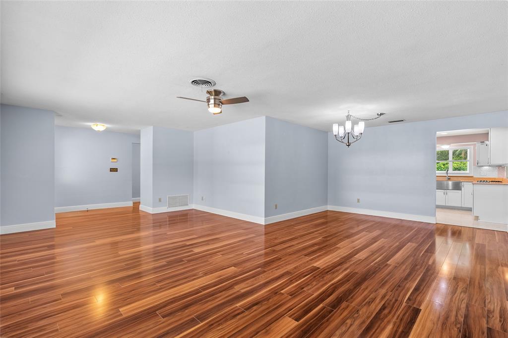 A spacious room with light blue walls, hardwood flooring, a ceiling fan, and a chandelier — 1341 RANCHWOOD DRIVE, CLEARWATER, FL