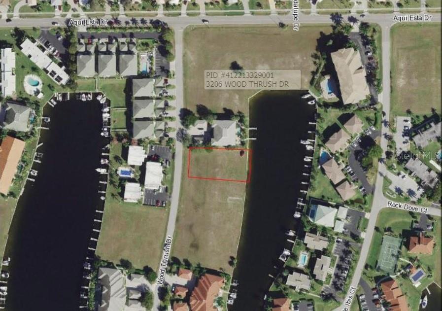 An aerial view shows a vacant rectangular waterfront lot outlined in red — 3234 WOOD THRUSH DRIVE, PUNTA GORDA, FL