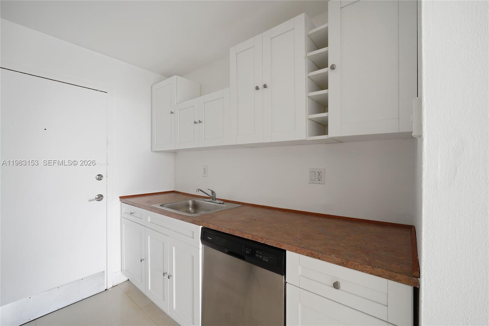 A kitchen features white cabinets, a stainless steel dishwasher, and a brown laminate countertop — 2000 NE 135th St # 1010, North Miami FL 33181, NORTH MIAMI, FL
