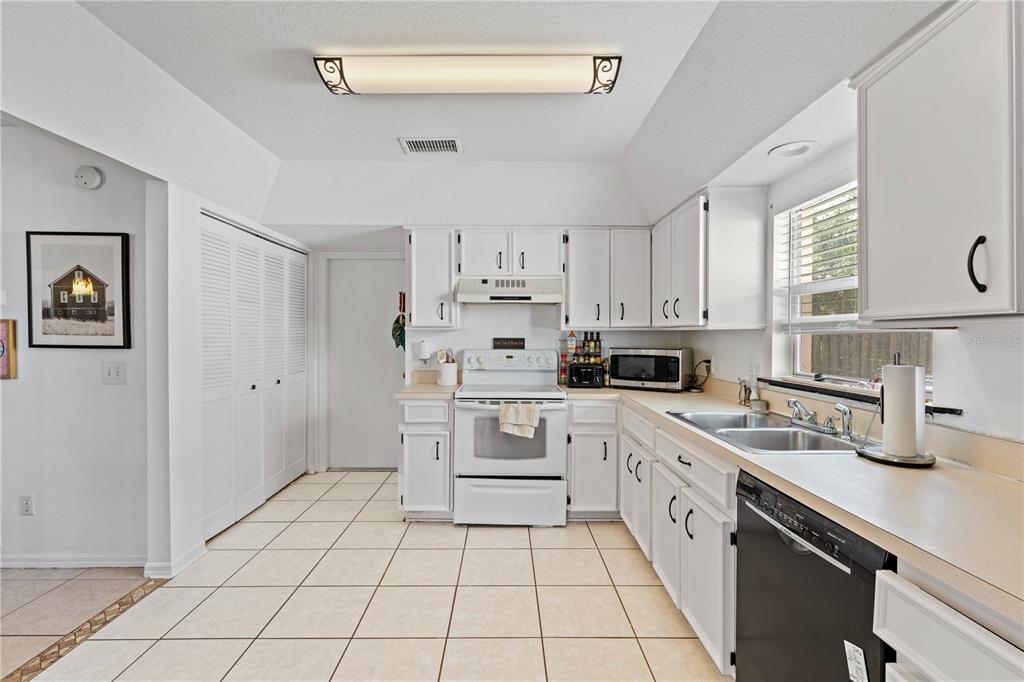 A kitchen with white cabinets, white appliances, tile flooring, and a double sink — 9758 FOX HOLLOW ROAD, TAMPA, FL