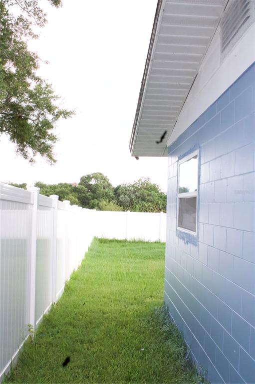 A side view of a blue concrete block house exterior next to a white vinyl fence — 315 AMADOR CIRCLE, ORLANDO, FL