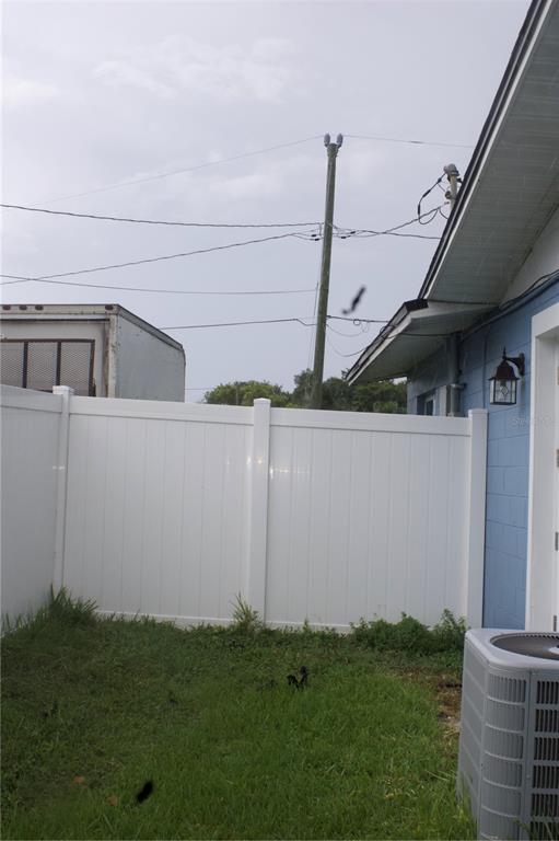 A white vinyl privacy fence encloses a small grassy backyard next to a blue house — 315 AMADOR CIRCLE, ORLANDO, FL