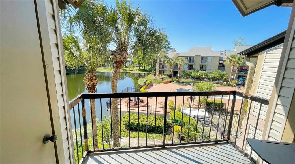 A balcony overlooks a pond, a swimming pool, and apartment buildings — 1972 LAKE ATRIUMS CIRCLE UNIT 200, ORLANDO, FL