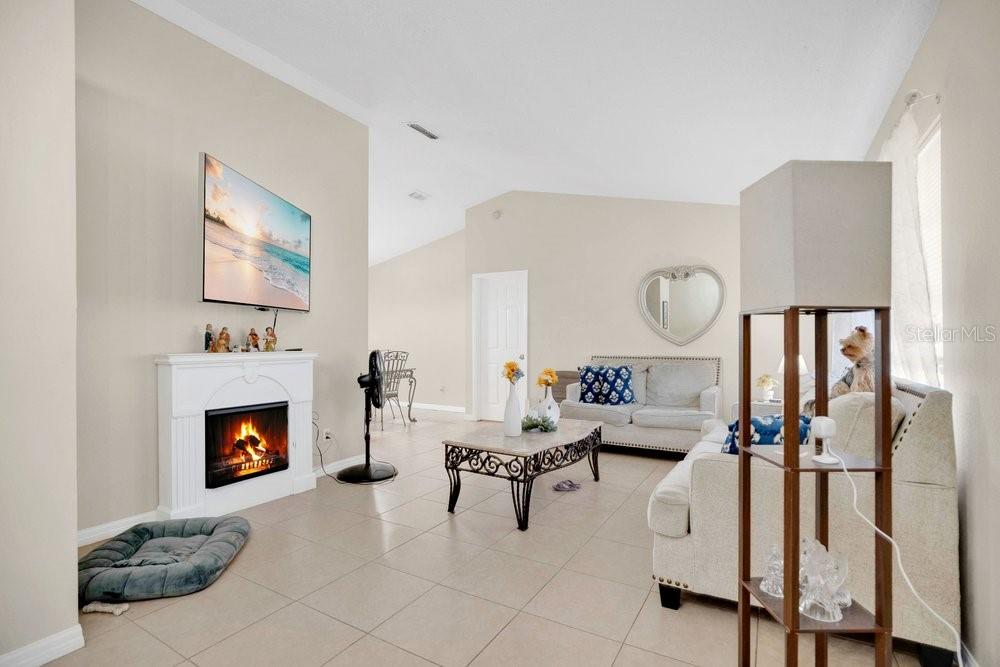 A living room features tile flooring, a fireplace with a television above, and neutral walls — 1141 DOYLE ROAD, DELTONA, FL