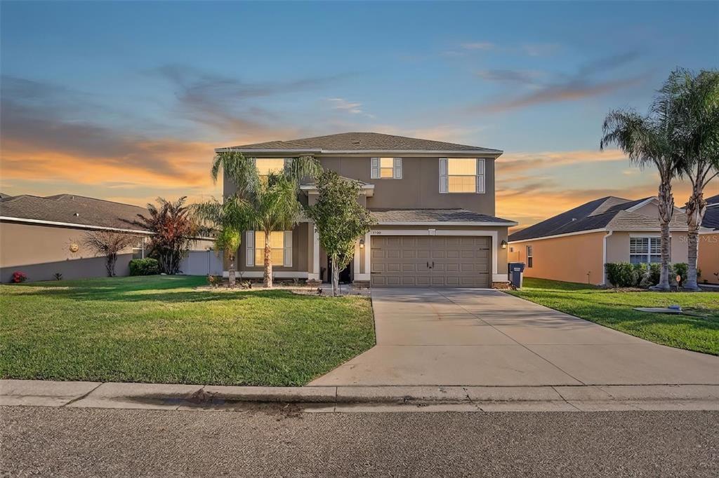 A two-story suburban house with a tan exterior, a two-car garage, and a concrete driveway — 13908 TENSAW DRIVE, HUDSON, FL