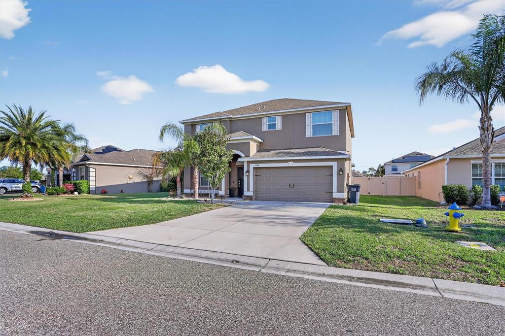 A two-story suburban house with a tan exterior, a concrete driveway, and a front lawn — 13908 TENSAW DRIVE, HUDSON, FL
