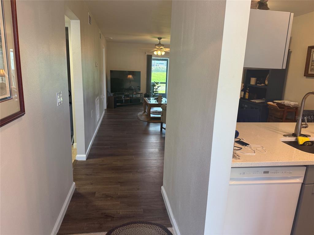 A view from a kitchen looking down a hallway toward a living room with flooring — 39132 COUNTY RD. 54 UNIT 2056, ZEPHYRHILLS, FL