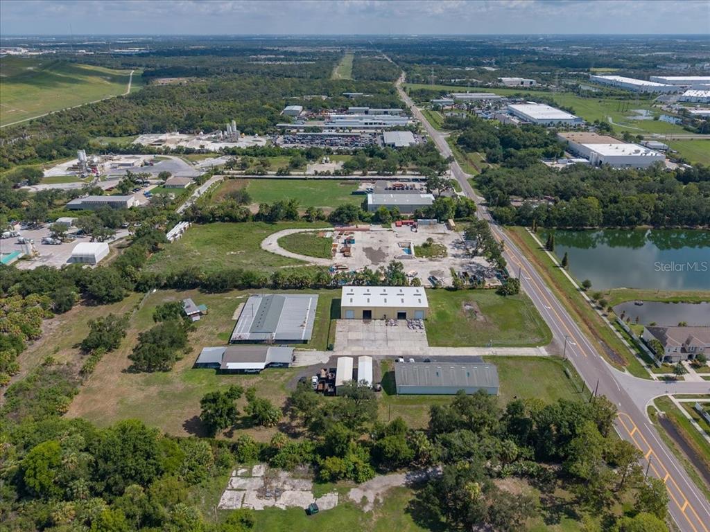 An aerial view shows industrial buildings, open land, and a road near a pond — 6901 S 78TH STREET, RIVERVIEW, FL
