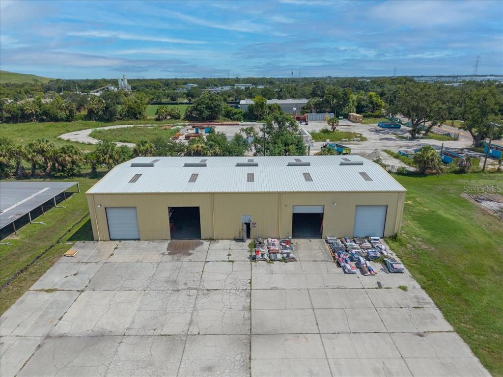 An aerial view of a single-story industrial warehouse building with four roll-up doors and a concrete lot — 6901 S 78TH STREET, RIVERVIEW, FL