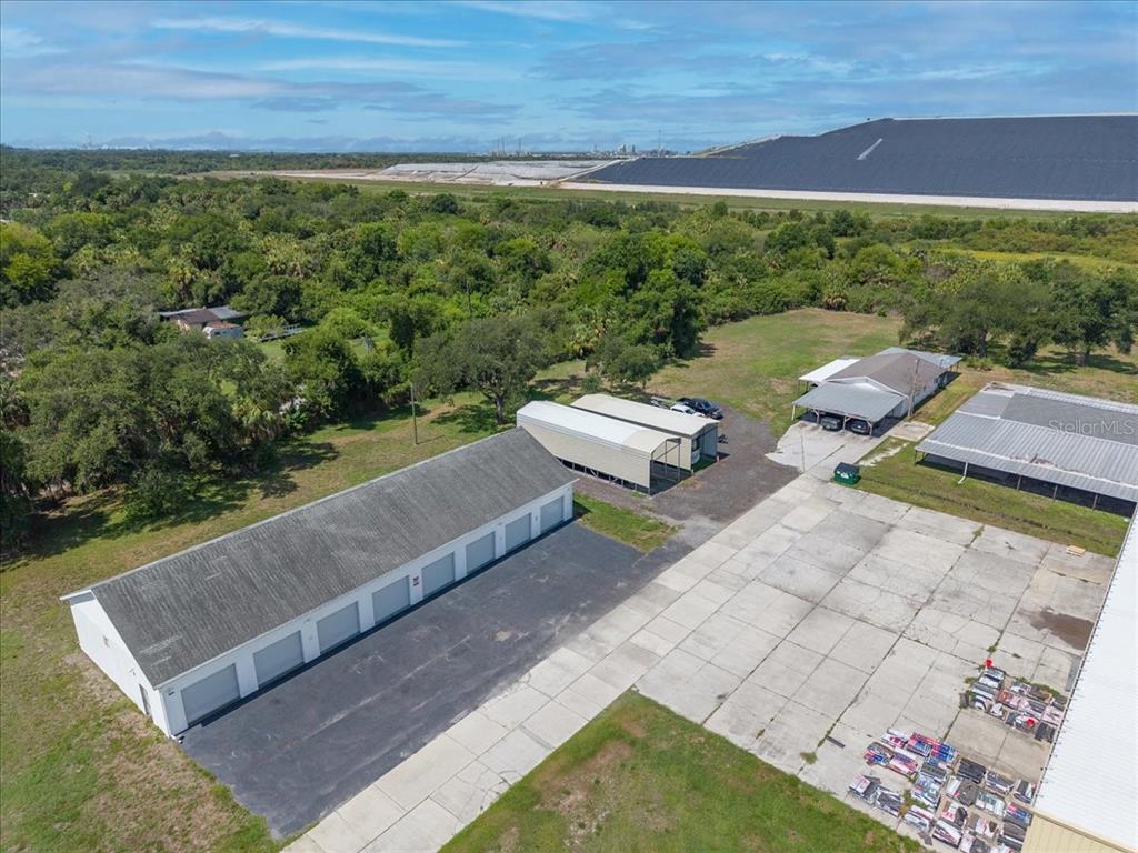 An aerial view shows a long storage building, a carport, and a house on land — 6901 S 78TH STREET, RIVERVIEW, FL