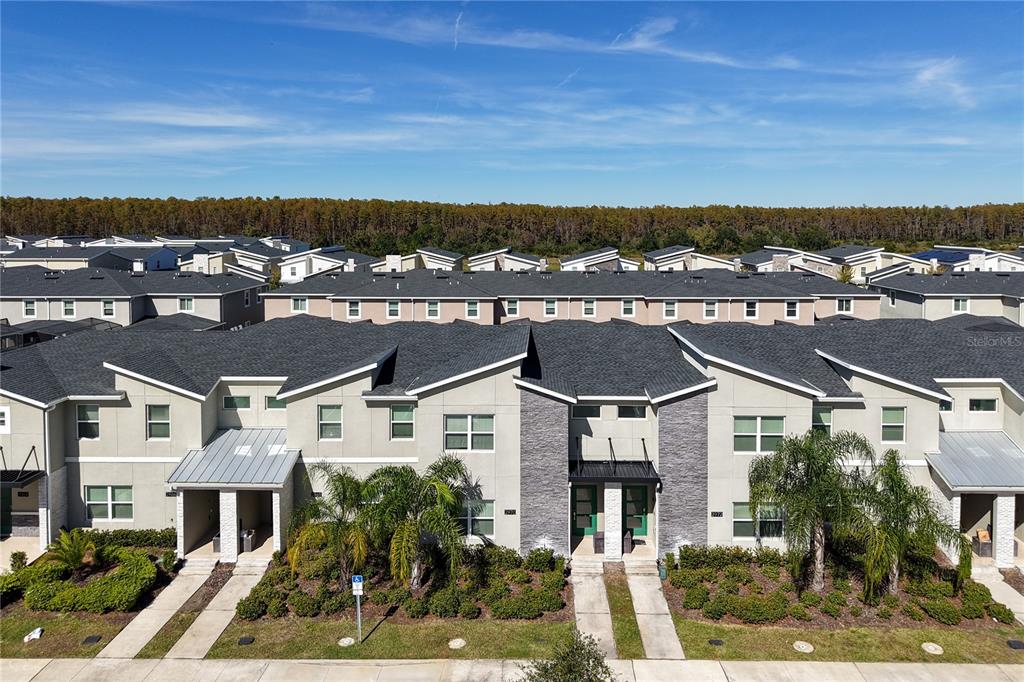 An aerial view shows a row of modern two-story townhomes with gray roofs and landscaping — 2970 PROTAGONIST STREET, KISSIMMEE, FL