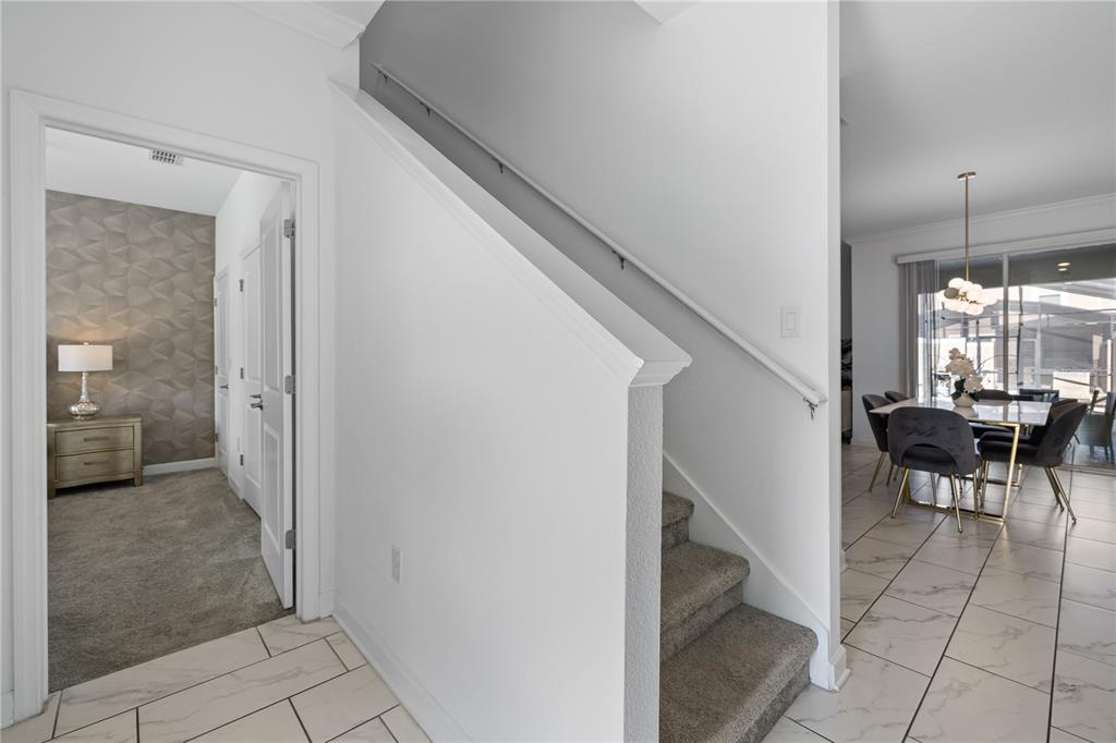 A view of a home interior showing a staircase, a carpeted room, and a dining area — 2970 PROTAGONIST STREET, KISSIMMEE, FL