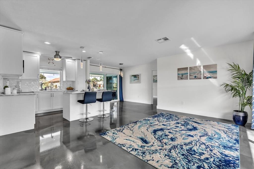 A modern kitchen with white cabinets and a breakfast bar opens into a living area — 2424 ROSA LANE, PUNTA GORDA, FL