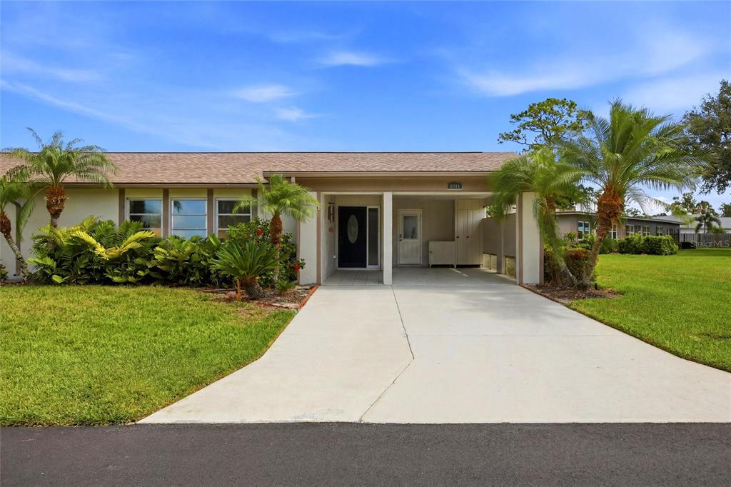A single-story house with a concrete driveway, a carport, and a landscaped front yard — 3721 COLLINS STREET UNIT 812, SARASOTA, FL
