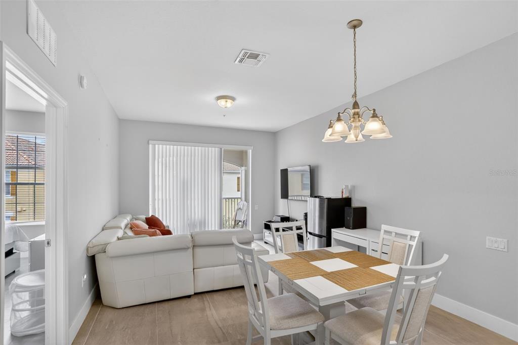 A living and dining area with light tile flooring, a white sectional, and a chandelier — 3332 ROBERT TRENT JONES DRIVE UNIT 40203, ORLANDO, FL