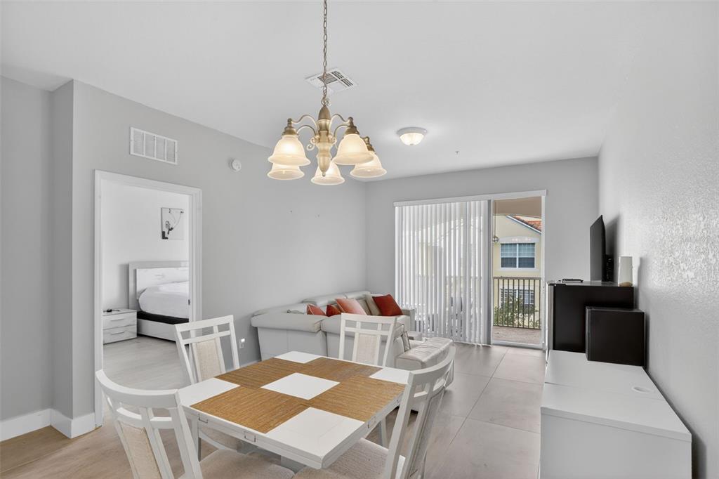 A dining area and living room with light tile floors, white furniture, and a balcony — 3332 ROBERT TRENT JONES DRIVE UNIT 40203, ORLANDO, FL