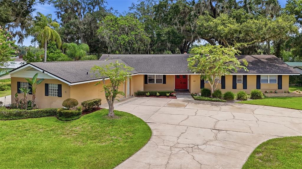 A single-story house with a tan exterior, dark roof, and a curved concrete driveway — 421 ELLIOTT AVENUE, SANFORD, FL