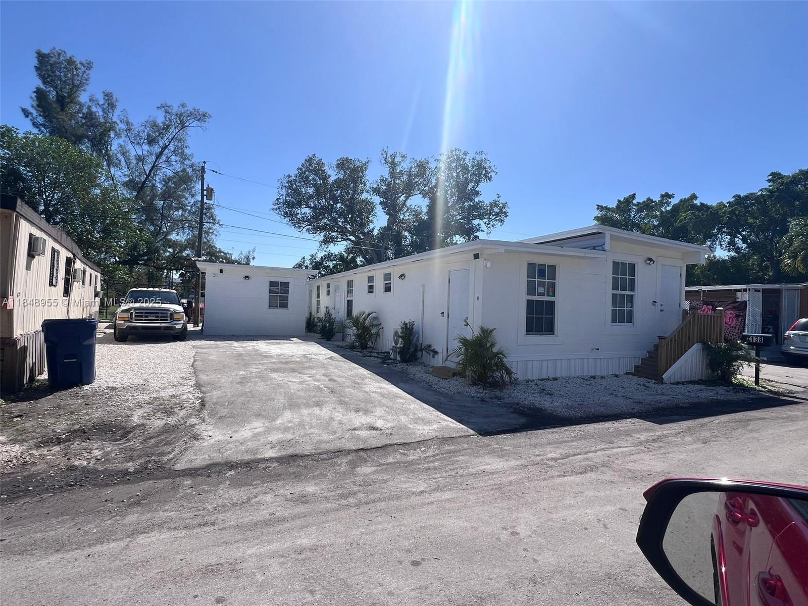 A white manufactured home features a concrete driveway, small landscaping, and a detached storage shed — 9674 NW 10th Ave, Miami FL 33150, MIAMI, FL