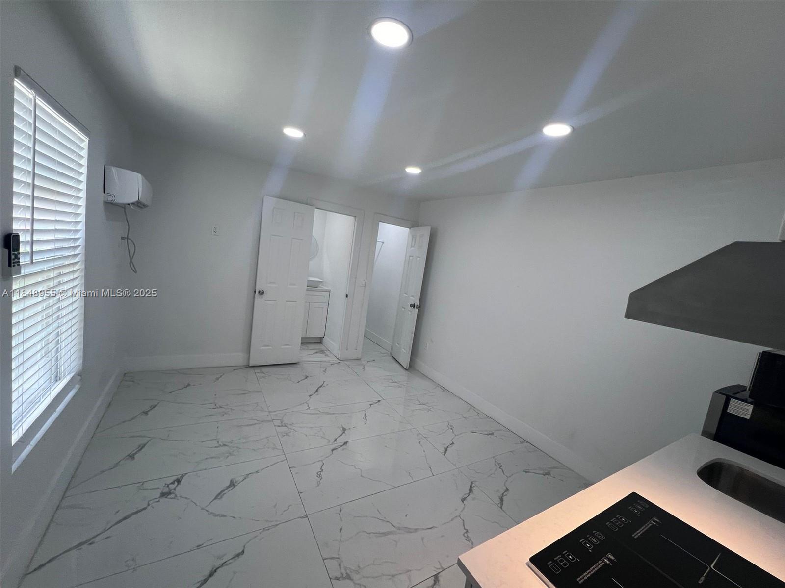 A kitchen area with white marble-patterned tile floors, recessed lighting, and two open doorways — 9674 NW 10th Ave, Miami FL 33150, MIAMI, FL