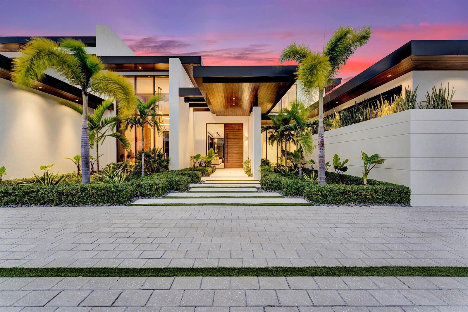 A modern home exterior features a paved driveway, palm trees, and a wooden front door — 829 Orchid Drive, Boca Raton FL 33432, BOCA RATON, FL
