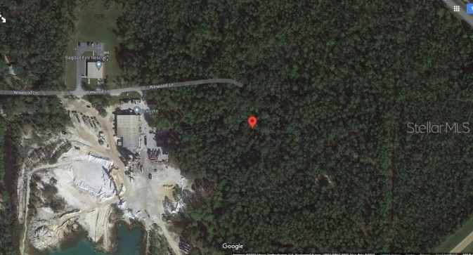This is a satellite map view showing a wooded lot marked with a red pin — 7157 WINDWOOD LANE, MILTON, FL