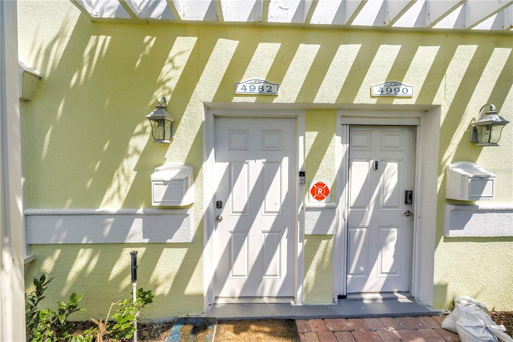 Two white front doors with house numbers and mailboxes on a light yellow exterior wall — 4982 COQUINA KEY DRIVE SE, ST PETERSBURG, FL