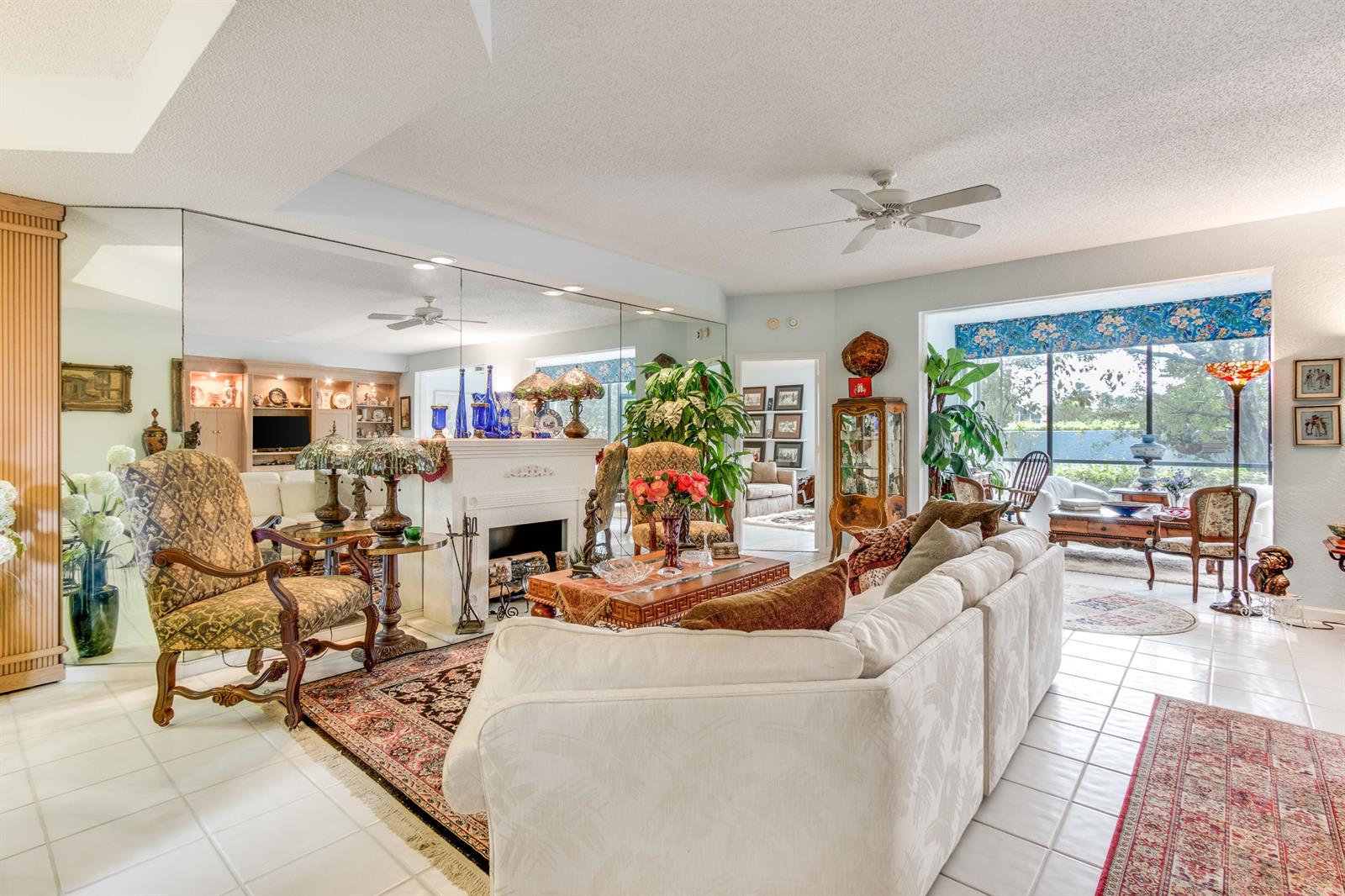 A living room features a white fireplace, mirrored wall, tile flooring, and a large sectional sofa — 11706 Briarwood Circle # 1, Boynton Beach FL 33437, BOYNTON BEACH, FL