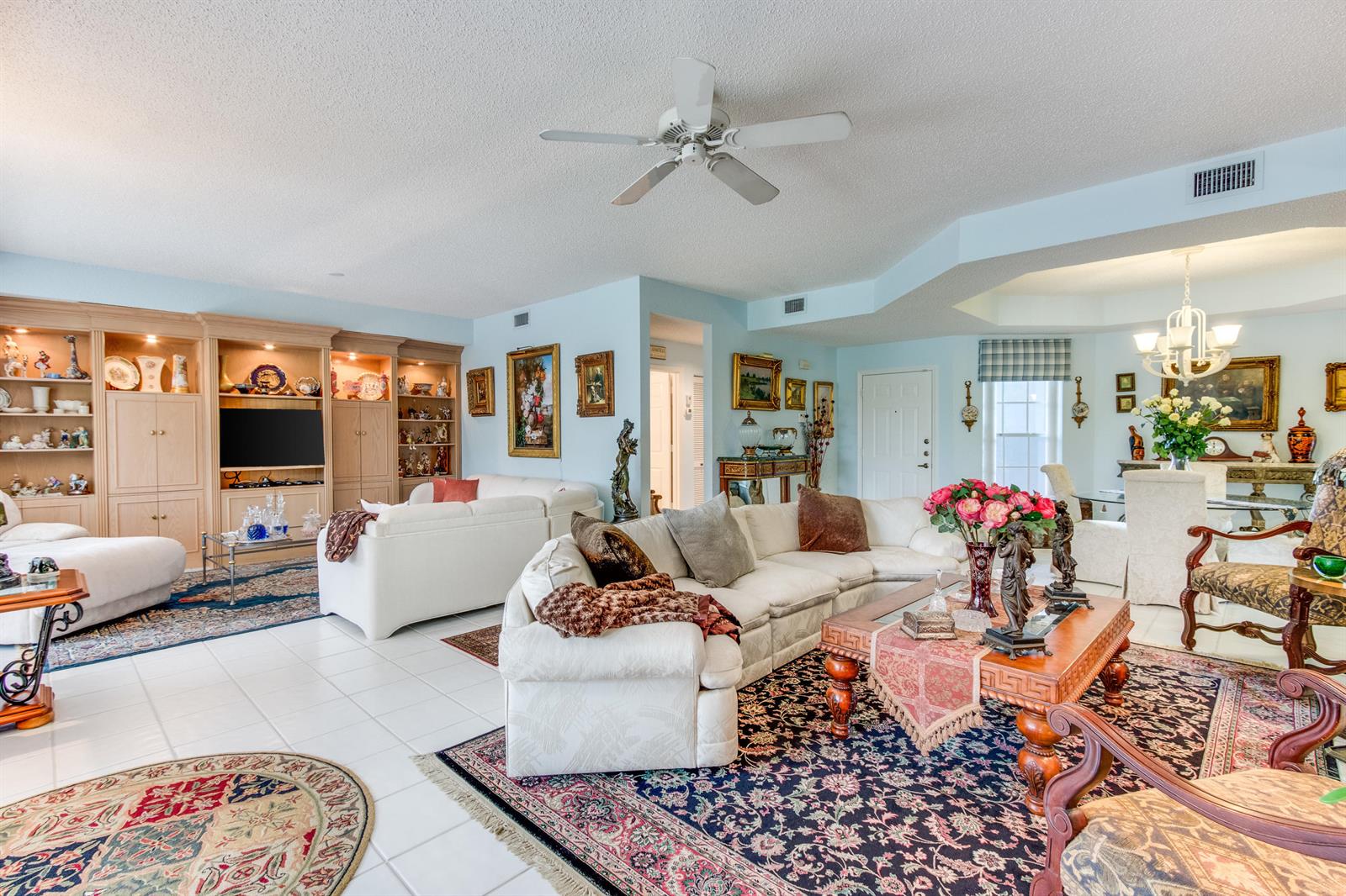 A spacious living room features light blue walls, tile flooring, built-in cabinetry, and two sectionals — 11706 Briarwood Circle # 1, Boynton Beach FL 33437, BOYNTON BEACH, FL