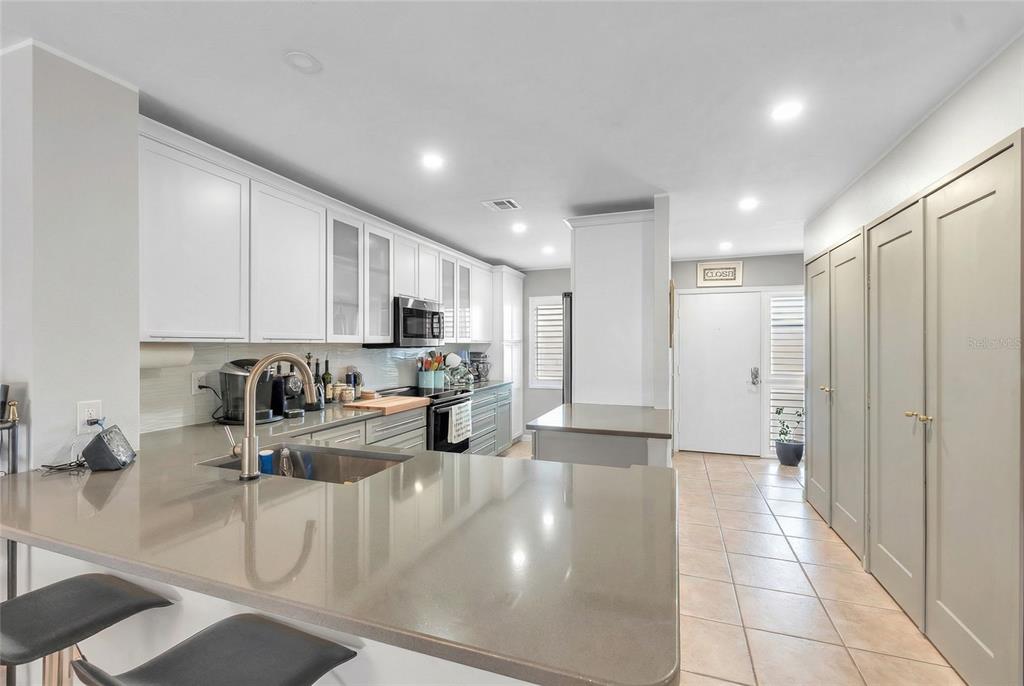 A kitchen with white cabinets, gray countertops, a breakfast bar, and tile flooring — 1650 1ST AVENUE W UNIT 307B, BRADENTON, FL