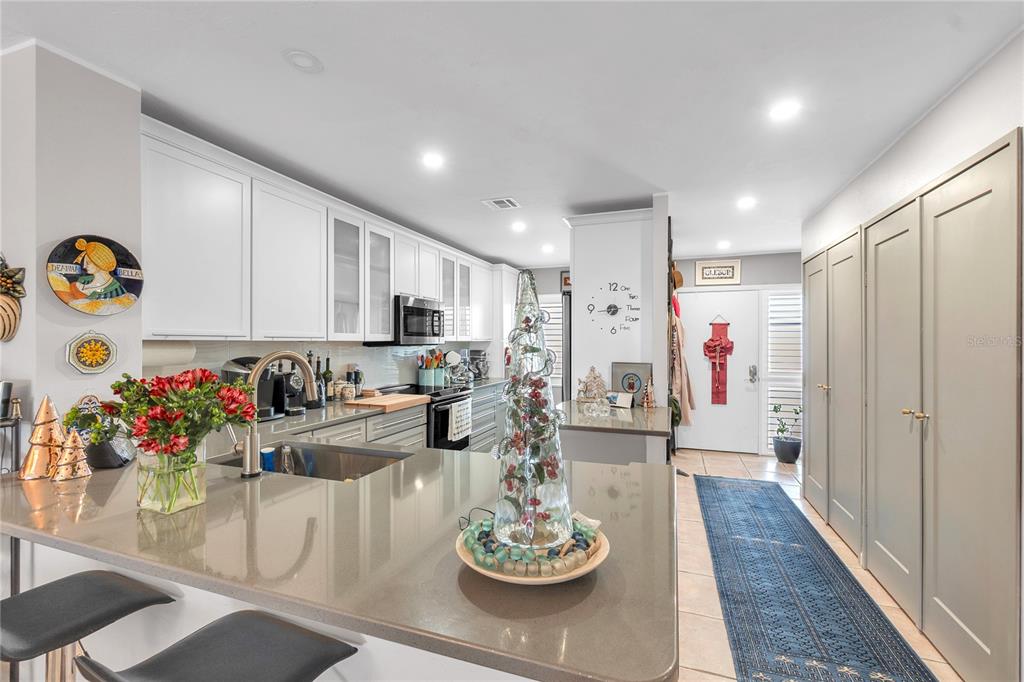 A kitchen features white cabinets, gray countertops, a central island, and a blue runner rug — 1650 1ST AVENUE W UNIT 307B, BRADENTON, FL