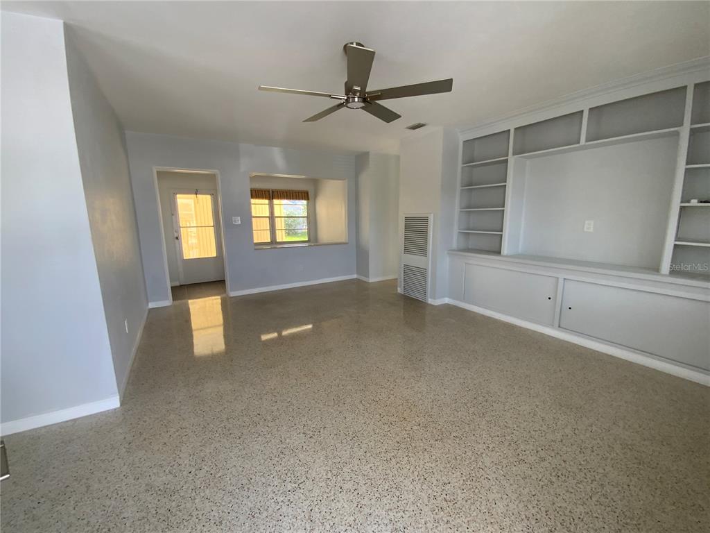 A living room features light gray walls, terrazzo flooring, a ceiling fan, and built-in shelving — 1404 COREY WAY S, SOUTH PASADENA, FL