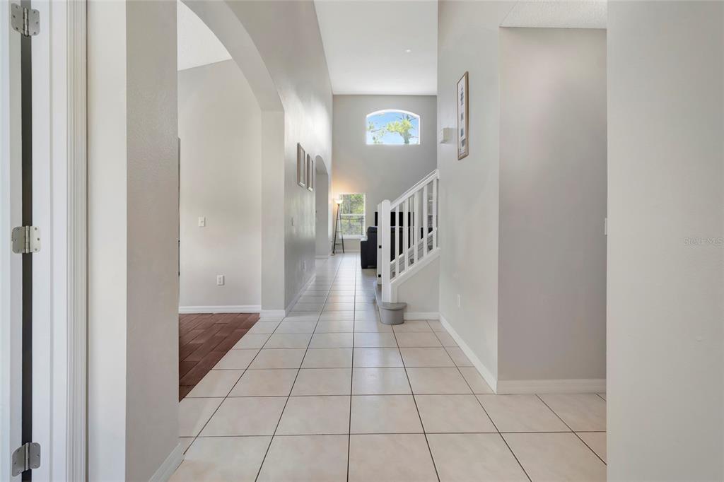 A tiled hallway leads toward a staircase and a living area with high ceilings — 4703 GOLDEN BEACH COURT, KISSIMMEE, FL