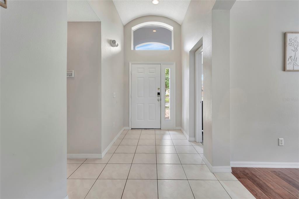 An entryway features light-colored floor tiles, a white front door, and a vaulted ceiling — 4703 GOLDEN BEACH COURT, KISSIMMEE, FL