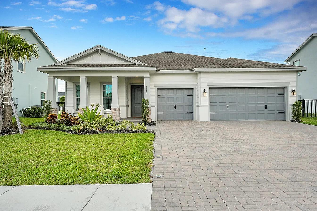 A single-story house with a gray garage, white siding, and a paved driveway — 1113 Tangled Orchard Trace, FL 33470, FL