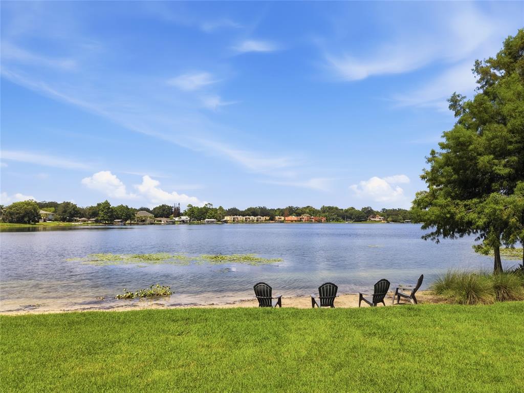 Four Adirondack chairs sit on a sandy beach overlooking a lake with distant houses — 3001 S OSCEOLA AVENUE, ORLANDO, FL