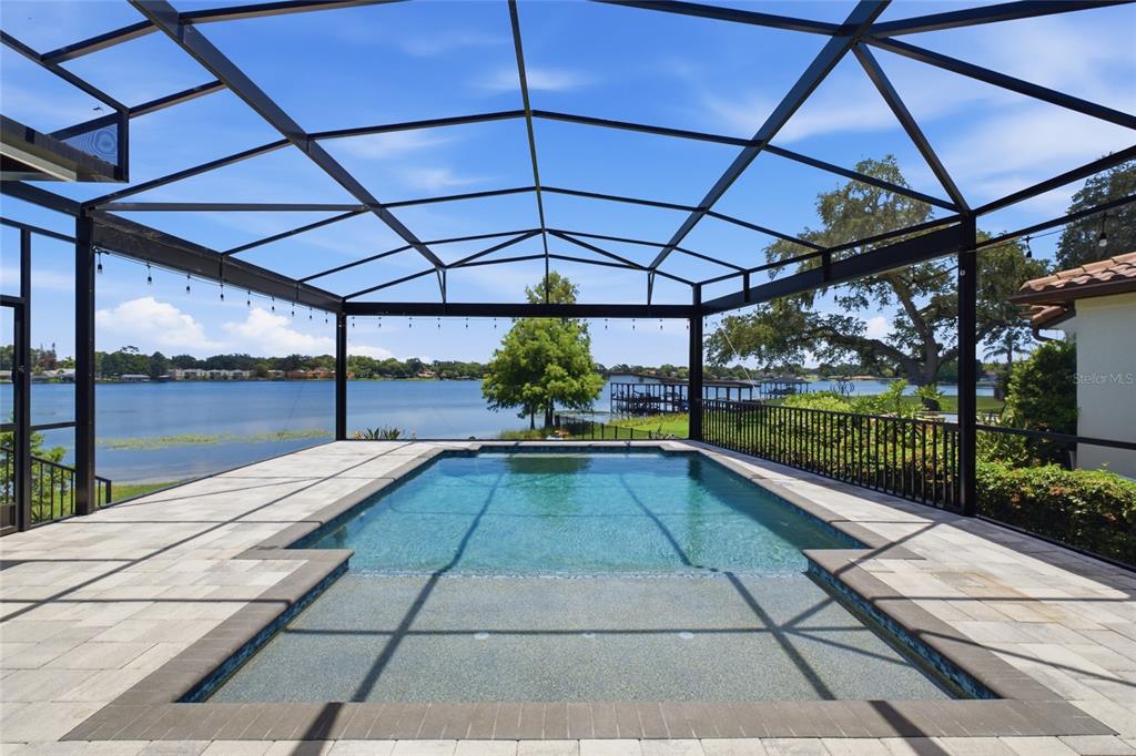 A screened-in pool patio overlooks a lake with a dock under a blue sky — 3001 S OSCEOLA AVENUE, ORLANDO, FL