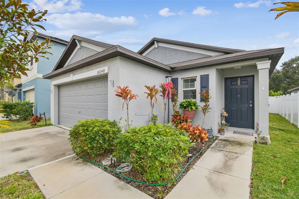 A single-story house with a gray garage, a dark front door, and landscaped front yard — 10248 CARLOWAY HILLS DRIVE, WIMAUMA, FL