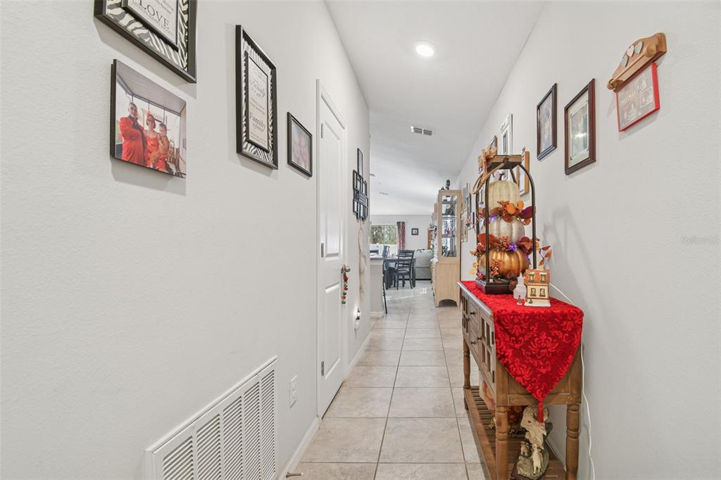 A tiled hallway features a console table with seasonal decor and framed photos on the walls — 10248 CARLOWAY HILLS DRIVE, WIMAUMA, FL