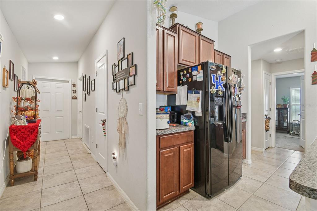 A hallway leads to a kitchen with dark wood cabinets and a black refrigerator — 10248 CARLOWAY HILLS DRIVE, WIMAUMA, FL
