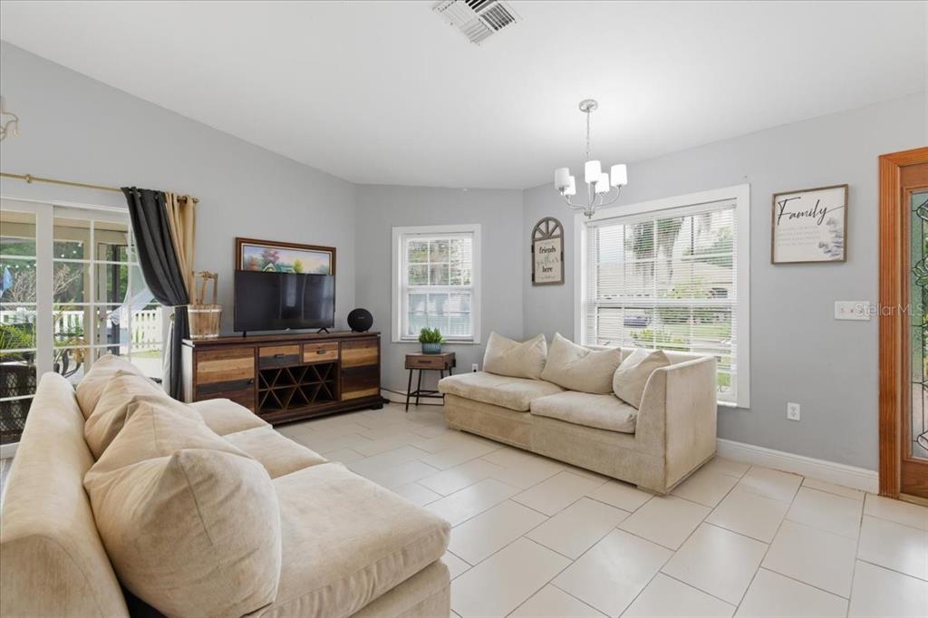 A living room features light gray walls, tile flooring, two beige sofas, and a television console — 3235 SILKWOOD LOOP, LAND O LAKES, FL