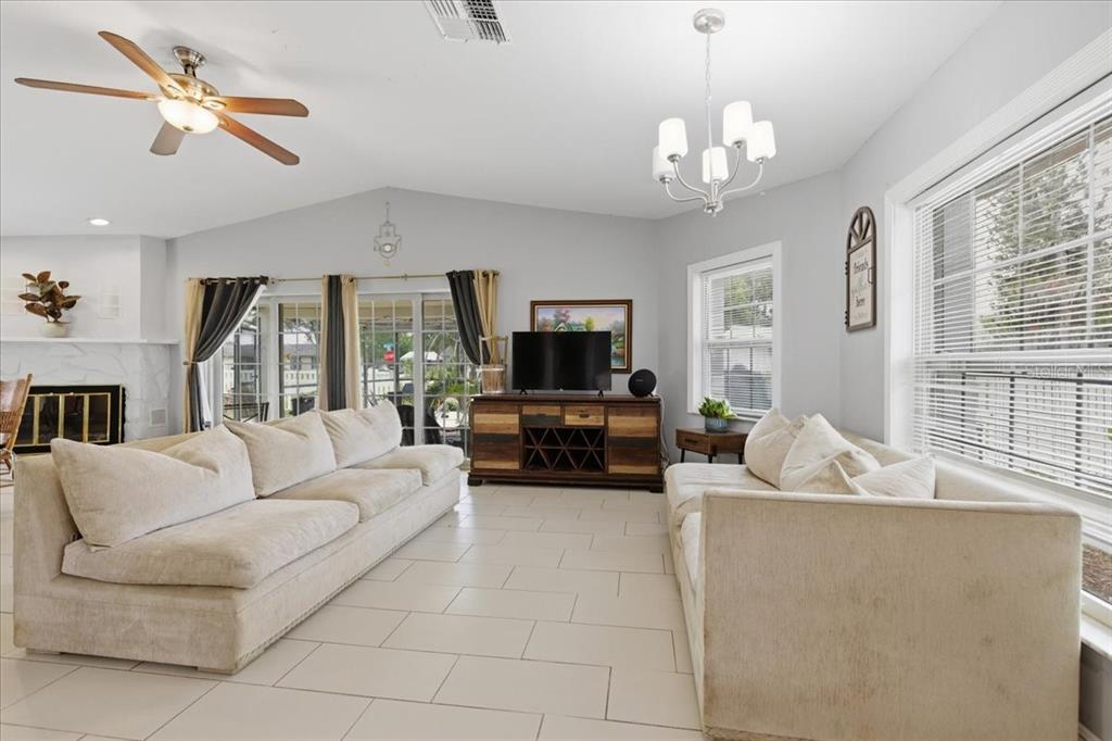 A living room features two beige sofas, a television console, and tile flooring — 3235 SILKWOOD LOOP, LAND O LAKES, FL