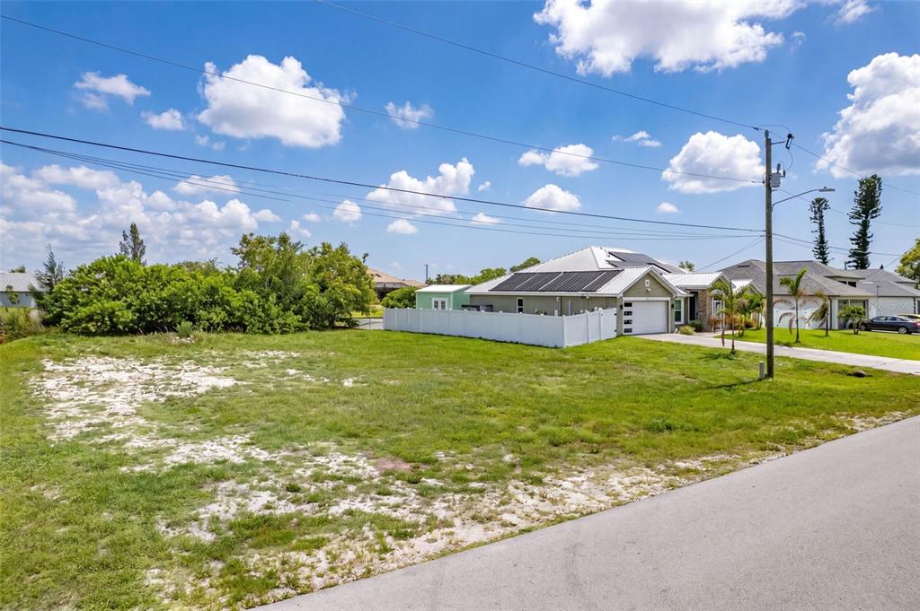 A vacant, grassy residential lot sits next to a house with a white fence — 623 NE 7TH TERRACE, CAPE CORAL, FL