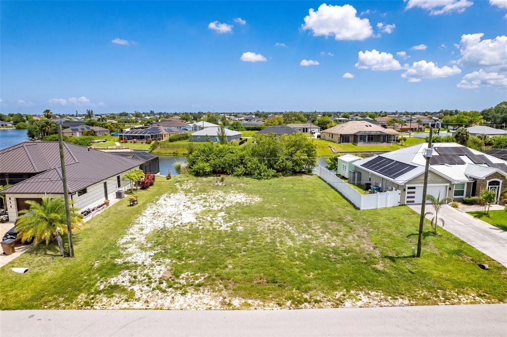 An elevated view of a vacant residential lot situated between two houses near a canal — 623 NE 7TH TERRACE, CAPE CORAL, FL