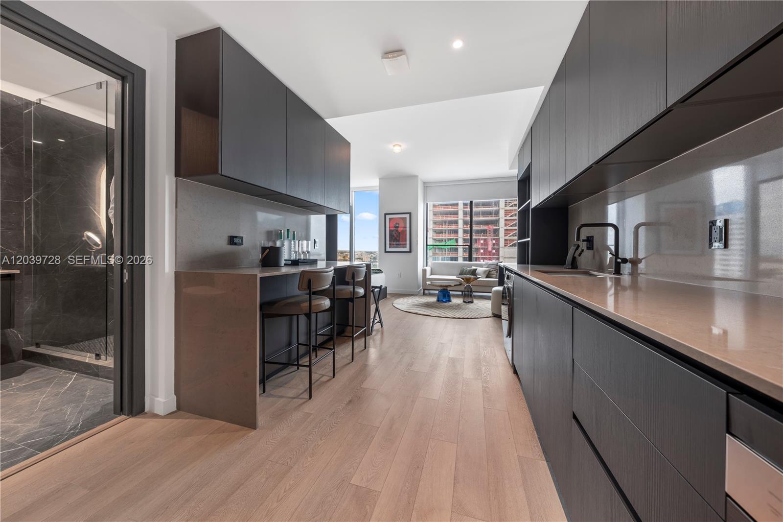 A modern galley kitchen features dark cabinetry, light countertops, and a breakfast bar — 20 NE 11th St # 2211, Miami FL 33132, MIAMI, FL