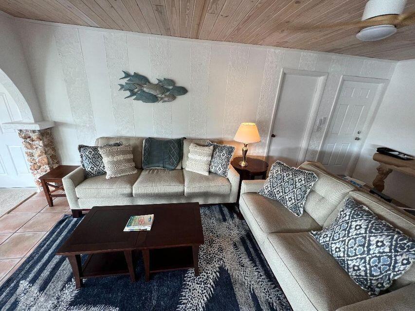 A living room features two beige sofas, a dark wood coffee table, and wood-paneled ceilings — 1540 Lantana Lane, FL 33043, FL