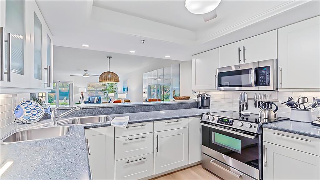 A kitchen features white cabinets, stainless steel appliances, and blue-flecked countertops — 1204 SIESTA BAYSIDE DRIVE UNIT 1204-D, SARASOTA, FL