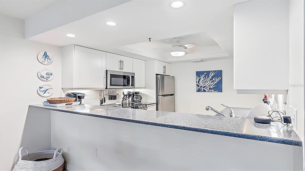 A kitchen features white cabinets, stainless steel appliances, and a gray granite breakfast bar — 1204 SIESTA BAYSIDE DRIVE UNIT 1204-D, SARASOTA, FL